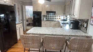 A kitchen with a central island, bar stools, a refrigerator, and a microwave. - Available Masters! Only 2.2 miles from the course. (Augusta)