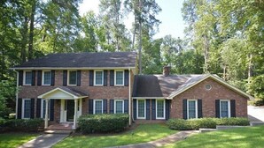 A two-story brick house with a front porch, a chimney, and a well-maintained lawn. - Available Masters! Only 2.2 miles from the course. (Augusta)