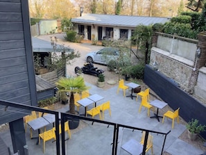 A courtyard with outdoor seating, a building in the background, and a parked motorcycle. - Citotel Monet (Honfleur)