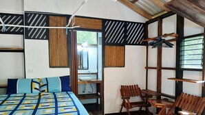Et værelse med en seng, en træbænk, et lille bord og et ophæng til tøj.