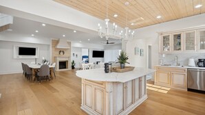 Une cuisine spacieuse dotée d’un grand îlot central, de planchers en bois et de meubles de cuisine modernes.