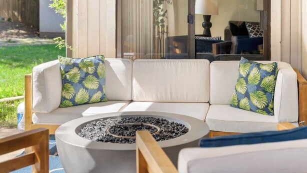 A sectional sofa with patterned cushions, a circular fire pit, and a wooden chair. - Spacious 3BR/2BA Central Sac – Fireside Comfort (Sacramento)
