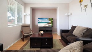A living room with a flat-screen TV, a sofa, a chair, and a coffee table. - Perfect Family Home w/ Private Outdoor Space! (San Diego)