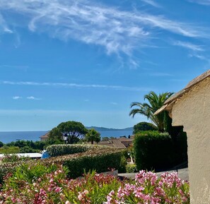A residential area with a clear view of the sea, a house with a sloped roof, and a well-maintained garden with pink flowers. - Villa Bella – Secure Domaine de la Croisette, Gulf of Saint-Tropez View (Sainte-Maxime)