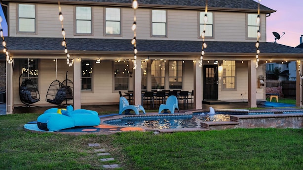 A house with a covered patio, outdoor seating, and a swimming pool. - Grand 6BR 3BA Pool Escape Round Rock (Round Rock)