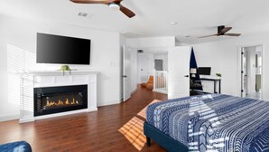 A modern bedroom with a fireplace, a large bed, and a ceiling fan. - Grand 6BR 3BA Pool Escape Round Rock (Round Rock)