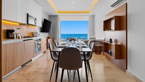 Een moderne keuken met een eetgedeelte, grote ramen en uitzicht op zee.