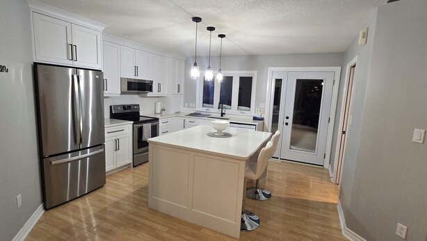 A modern kitchen with white cabinets, stainless steel appliances, and a central island. - Modern country house w/firepit. (Alma)