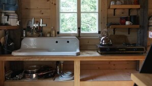 A wooden cabin kitchen with a white sink, a coffee maker, and a stove. - Les Cabines St-O - 2 (St-Onésime d'Ixworth)