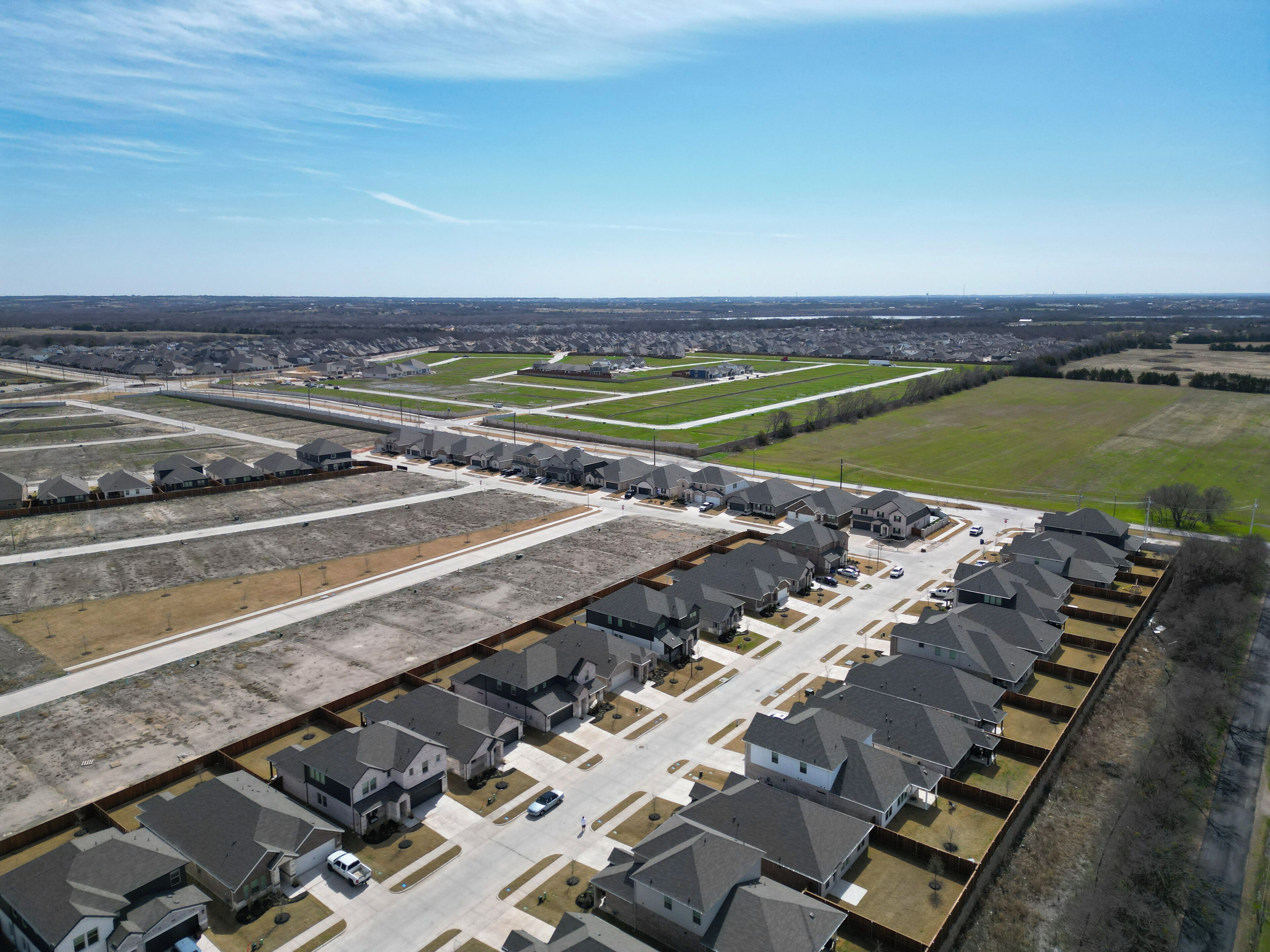 Vista aérea de uma área residencial com várias casas, ruas e áreas verdes.
