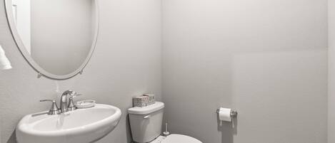 A bathroom with a sink, toilet, and mirror.