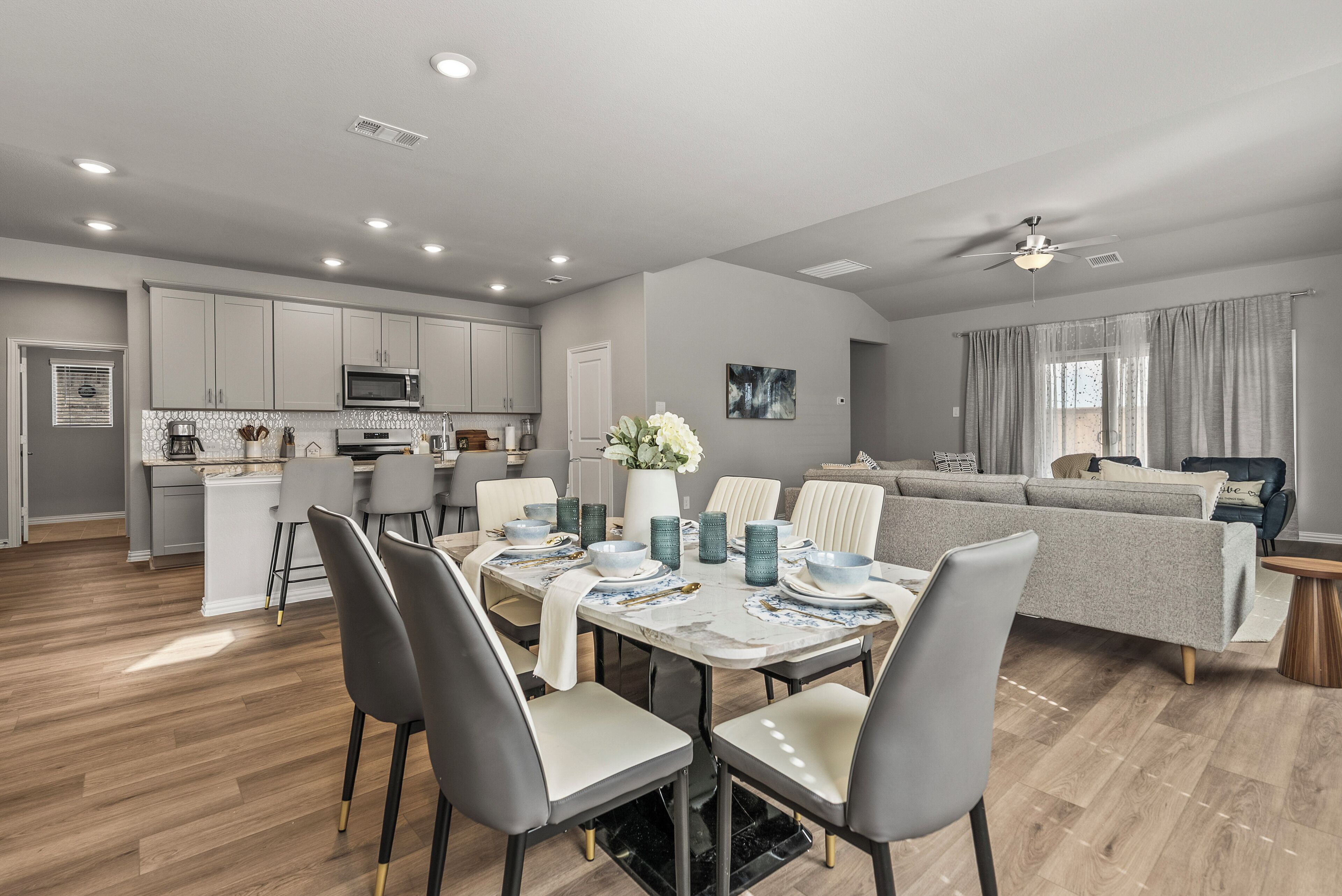 A modern kitchen with white cabinets, a microwave, and a dining area with a table set for four.