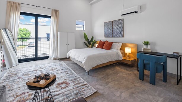 A modern hotel room with a large bed, a desk, a chair, a small table with a lamp, and a view of the outdoors. - Studio | near Aquarium, Coolridge Park (Chattanooga)