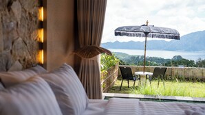 A bedroom with a view of a balcony, a bed, and a table with chairs. - Mount Valley Inn Kintamani (Kintamani)
