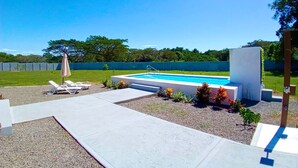 A backyard with a swimming pool, lounge chairs, and a covered seating area. - Quinta Los Monos : Private Swimming Pool : Pet-friendly (Paquera)
