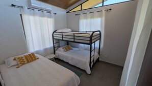 A room with two bunk beds, a small round table, and a window with curtains. - Quinta Los Monos : Private Swimming Pool : Pet-friendly (Paquera)