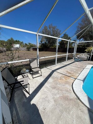 A covered outdoor area with a pool, concrete flooring, and a chair. - Pet Friendly, Pool (Punta Gorda)