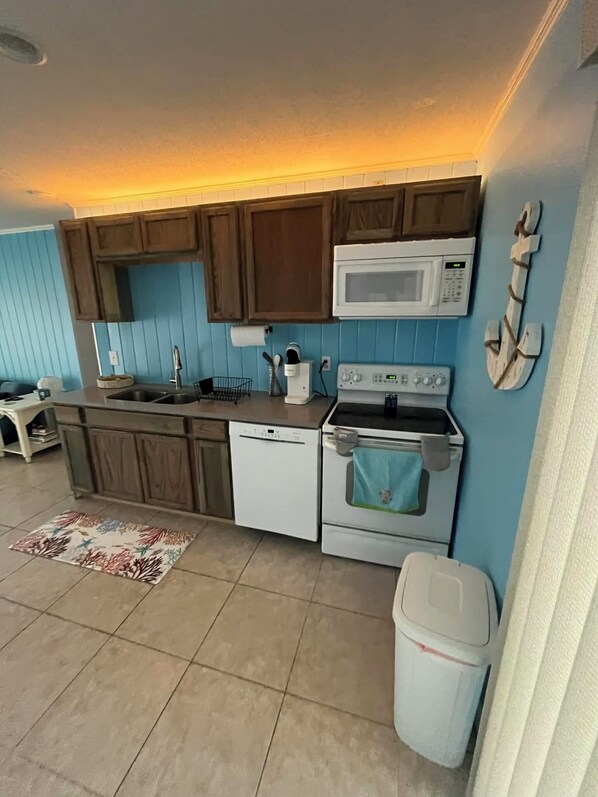 A kitchen with wooden cabinets, a white microwave, a dishwasher, and a stove. - Pet Friendly, Pool (Punta Gorda)