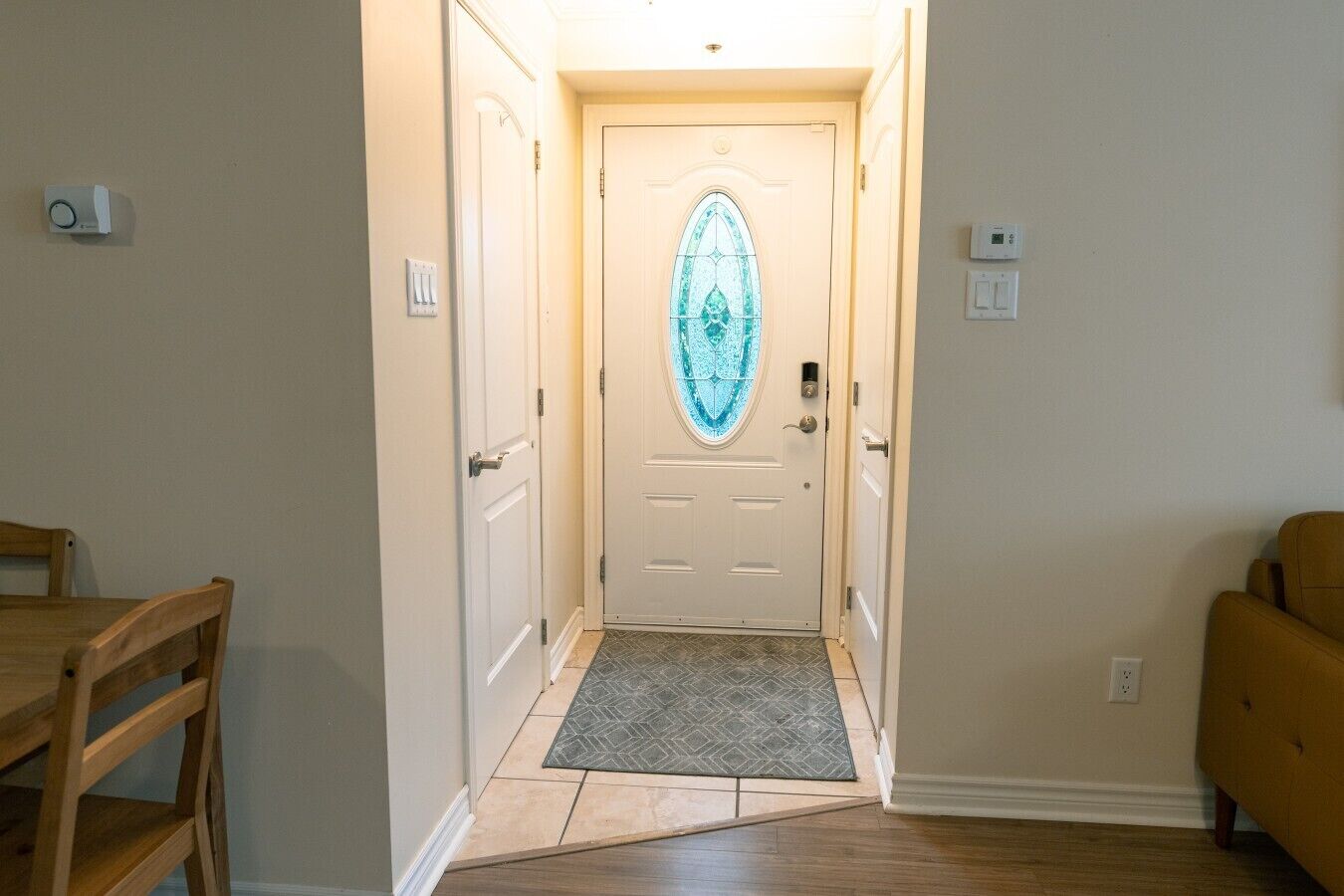 Un couloir avec une porte, une chaise en bois, un tapis et un canapé.