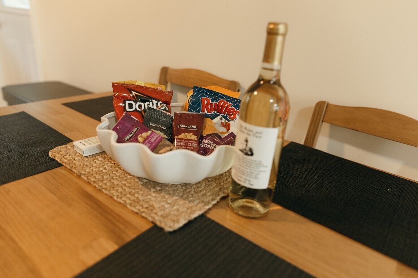 A table with a bowl containing snacks and a bottle of wine.
