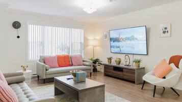 A living room with a sofa, armchair, coffee table, TV, and decorative items.