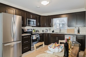 A modern kitchen with dark wood cabinets, stainless steel appliances, a microwave, oven, and a dishwasher.