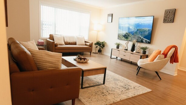 Una sala de estar con sofá, mesa de centro, sillón, televisor y un cuadro en la pared.