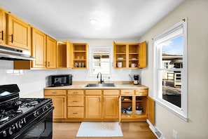 A modern kitchen with wooden cabinets, a built-in microwave, a stove, and a window providing a view of the outside.