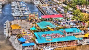 A waterfront restaurant with a prominent 'Gunbo Love' sign, a dock with boats, and a parking area. - 7029- Family Friendly - Gulf Shores - Pools-beach (Gulf Shores)