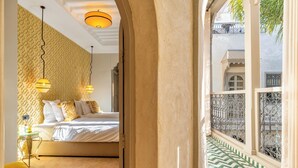 A bedroom with a patterned wall, a bed, and a window with a view of a building. - Suites and Spa - BY XO Riad (Marrakech)