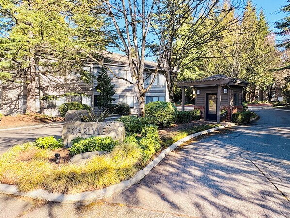 A residential area with a stone sign reading "Carlyle," surrounded by well-maintained landscaping and trees. - Downtown Bellevue 2BR Condo Free Reserved Parking (Bellevue)