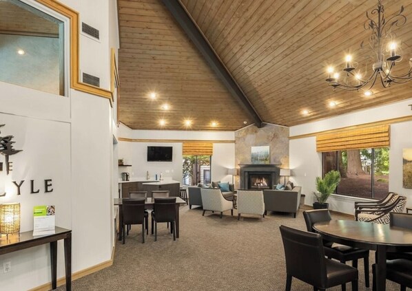 A spacious living area with a fireplace, comfortable seating, and a kitchen in the background. - Downtown Bellevue 2BR Condo Free Reserved Parking (Bellevue)