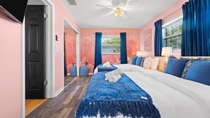 Hotelkamer met een bed, twee nachtkastjes, een plafondventilator en een raam met gordijnen.