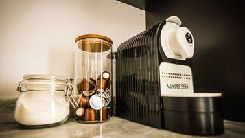 Une machine à café portant la marque « MIXPRESSO » et un bocal en verre avec un couvercle en métal et une cuillère, posés sur un plan de travail.