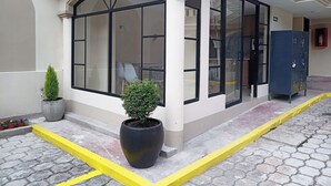 A building with large windows, a potted plant, and a yellow curb line. - Hostal Tayupanda (Quito)