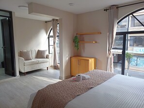 A hotel room with a bed, a sofa, a wooden cabinet, and a large window with a view of the outside. - Hostal Tayupanda (Quito)