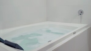 A modern bathroom with a white bathtub, a window, and a wall-mounted faucet. - Hostal Tayupanda (Quito)