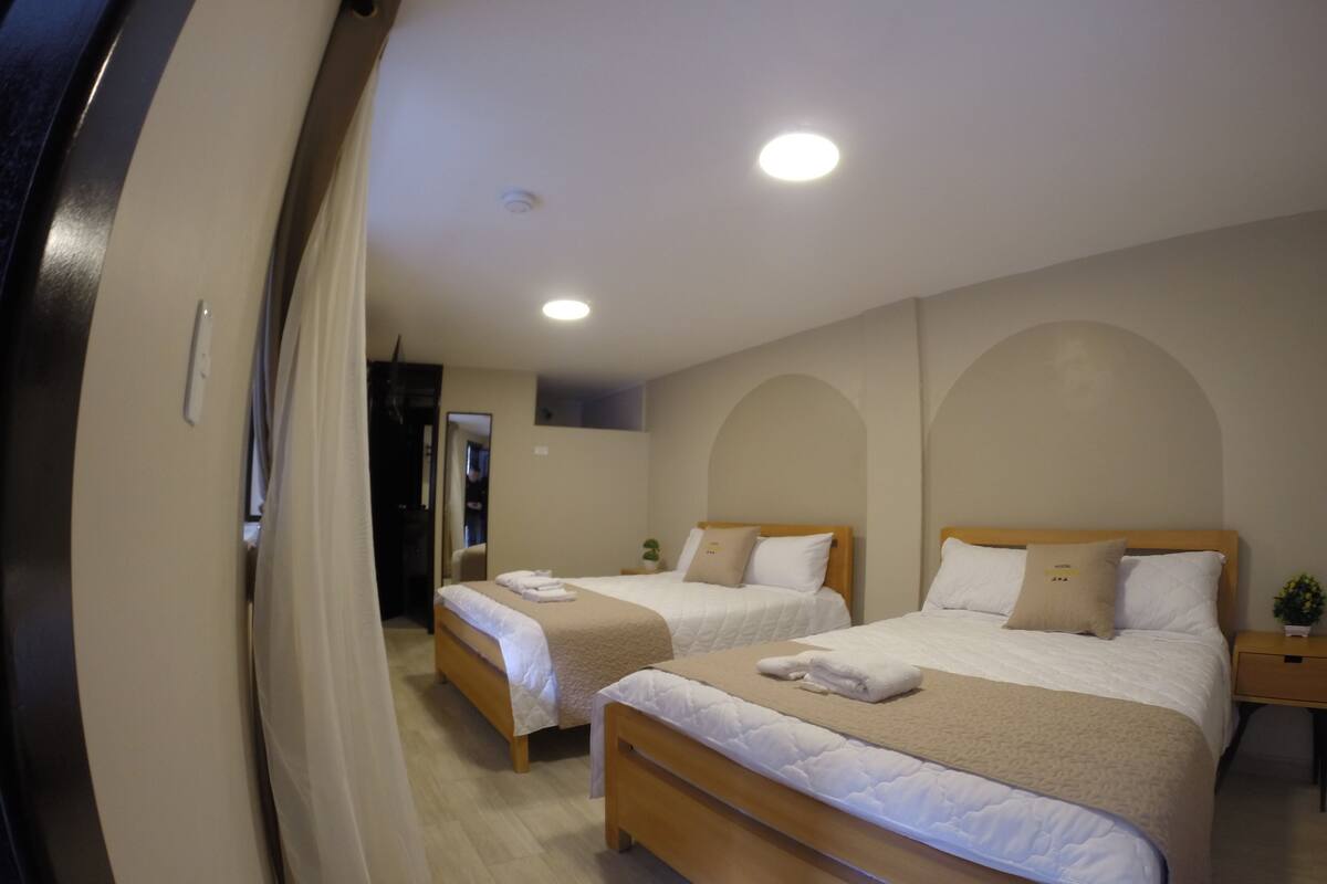 Een hotelkamer met twee bedden, een klein nachtkastje met een plant, en een spiegel aan de muur.