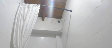 Een kleine, afgesloten douchecel met toilet en een handdoekhouder.