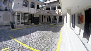 A courtyard with cobblestone paving, a covered seating area, and a building with multiple balconies and large windows. - Hostal Tayupanda (Quito)
