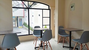 A modern interior with a large window, a round table, and four chairs. - Hostal Tayupanda (Quito)