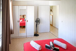 A bedroom with a bed, a fan, and a mirror.
