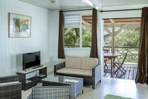 A room with a TV, sofa, and wicker furniture.