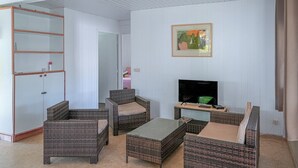 Ein Zimmer mit Korbmöbeln, einem Fernseher und einem Bild an der Wand.