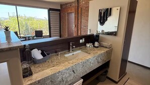 Une salle de bain moderne avec un comptoir en granit, un grand miroir et une vue sur l’extérieur.