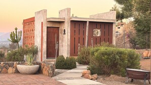 Un bâtiment moderne avec une porte rouge, des murs en pierre et un cactus dans un pot.