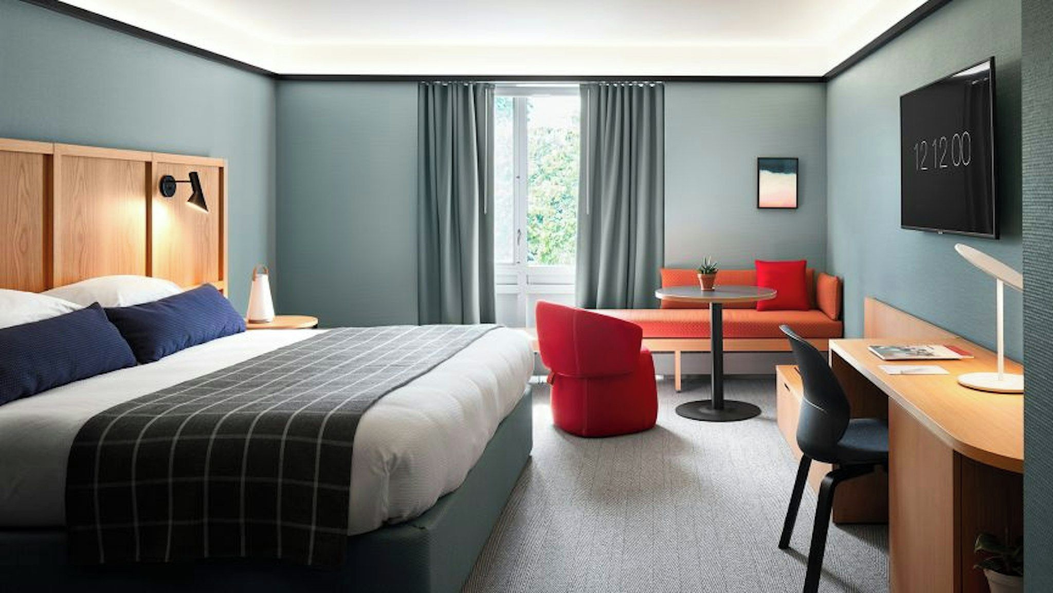 A hotel room with a bed, a desk, a red chair, a small table, and a TV mounted on the wall.