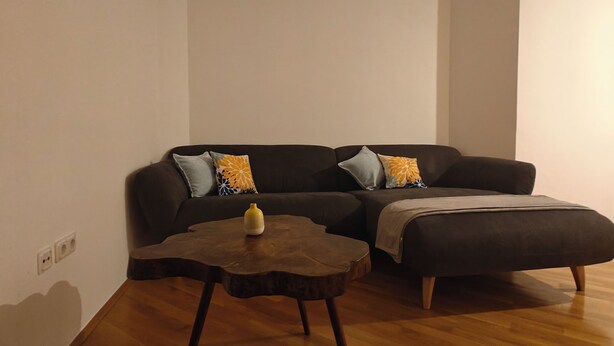 A modern living room with a dark-colored sofa, two wooden coffee tables, and a small decorative vase. - Retro Retreat! Reset-Recharge-Rewind (Bochum)