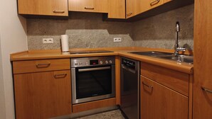 A compact kitchen with wooden cabinets, a Bosch oven, a dishwasher, and a granite countertop. - Retro Retreat! Reset-Recharge-Rewind (Bochum)
