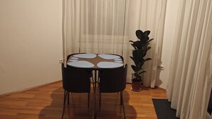 A small dining area with a round table and two chairs, a potted plant, and sheer curtains. - Retro Retreat! Reset-Recharge-Rewind (Bochum)